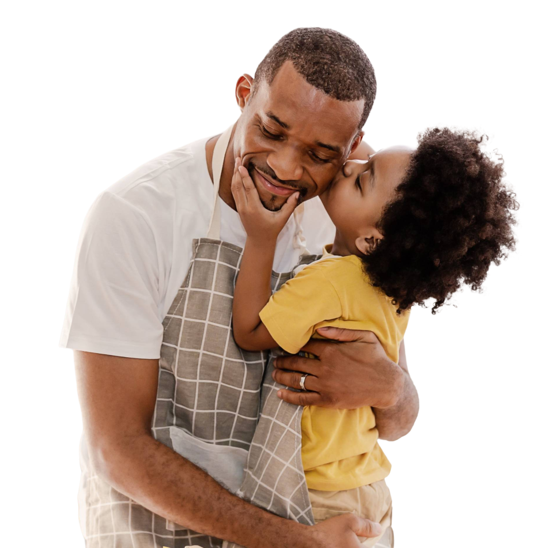 Young boy with thick coiled hair kisses dad in apron on the cheek.