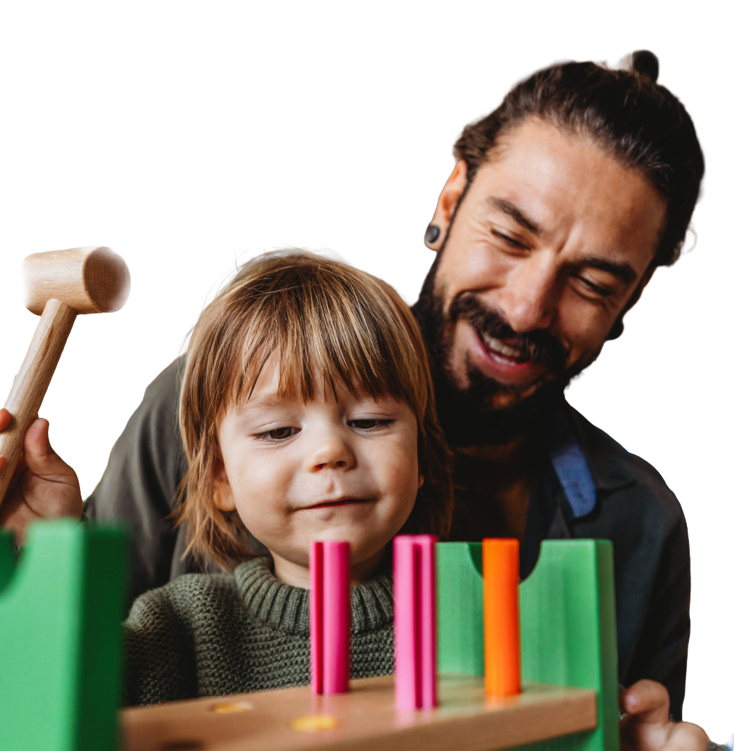 Dad with a top knot and ear gauges plays with toddler and hammer toy.